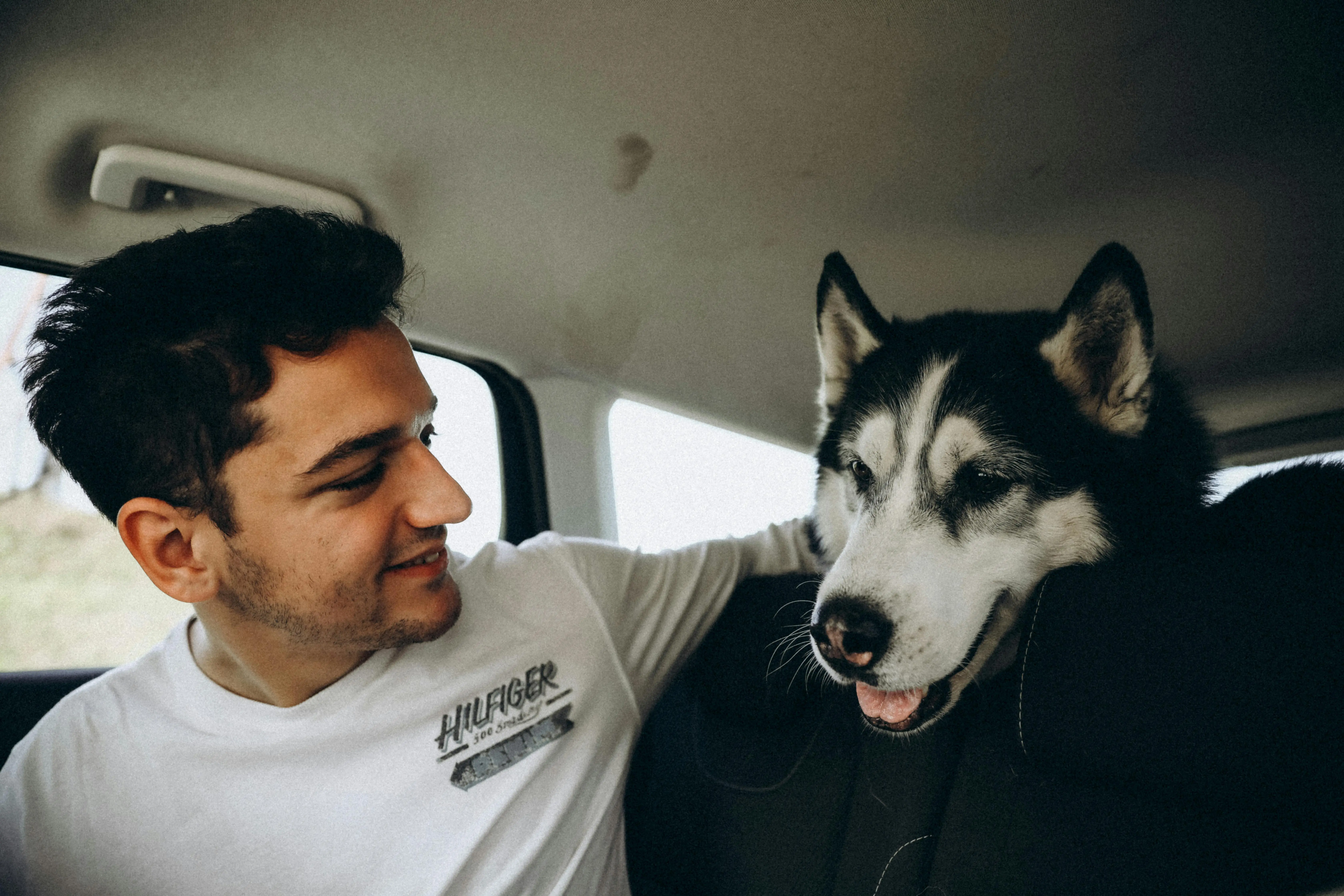 Hombre y mascota en auto, sonrientes y felices.