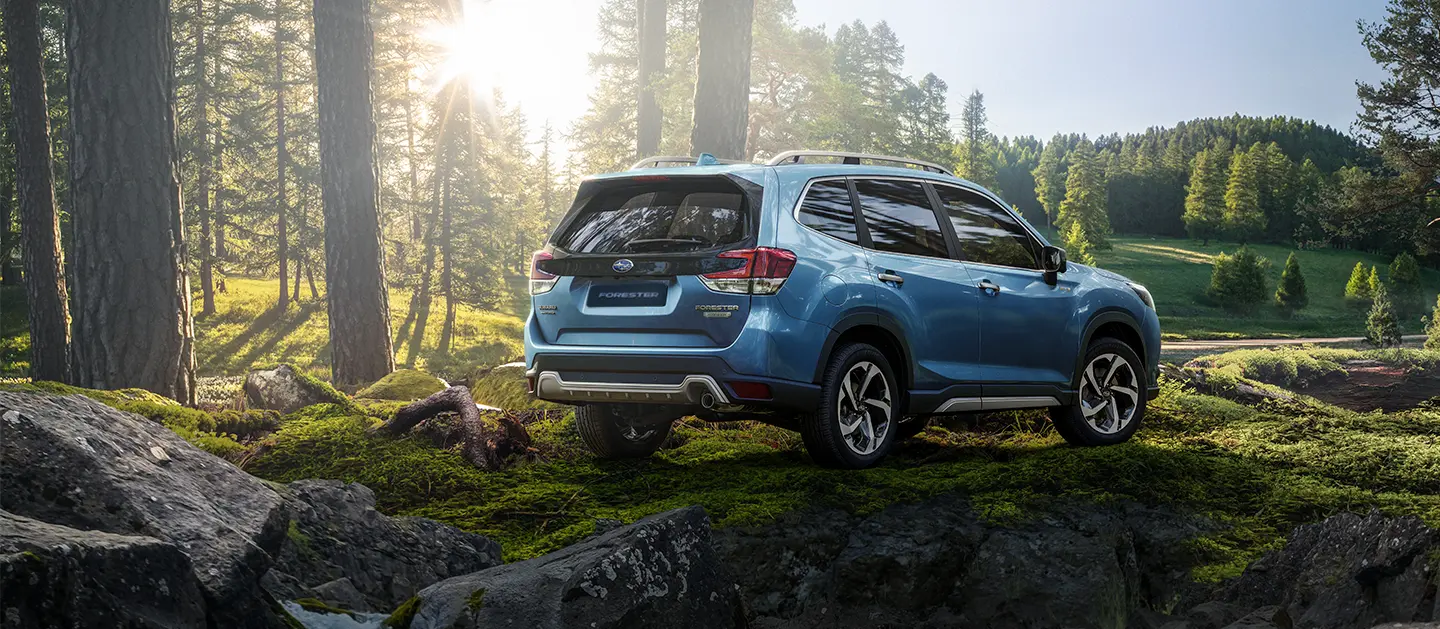 Subaru Forester Hyvrid estacionado sobre rocas y vegetación de fondo.