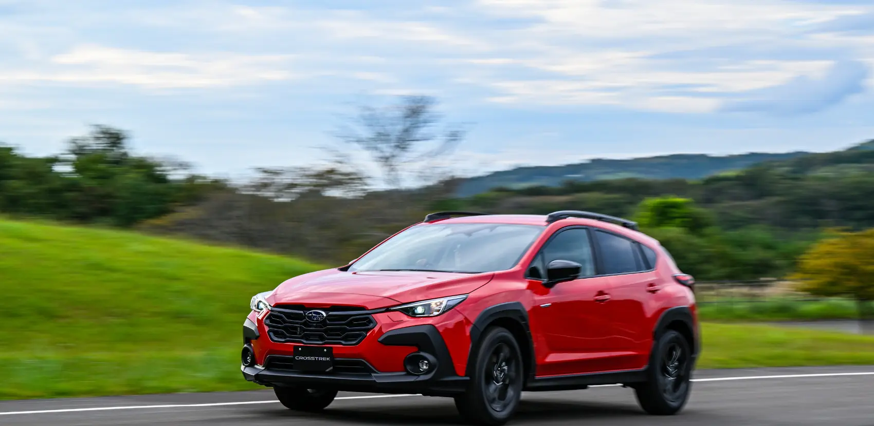 Subaru Crosstrek Hybrid en carretera a velocidad con vegetación de fondo.